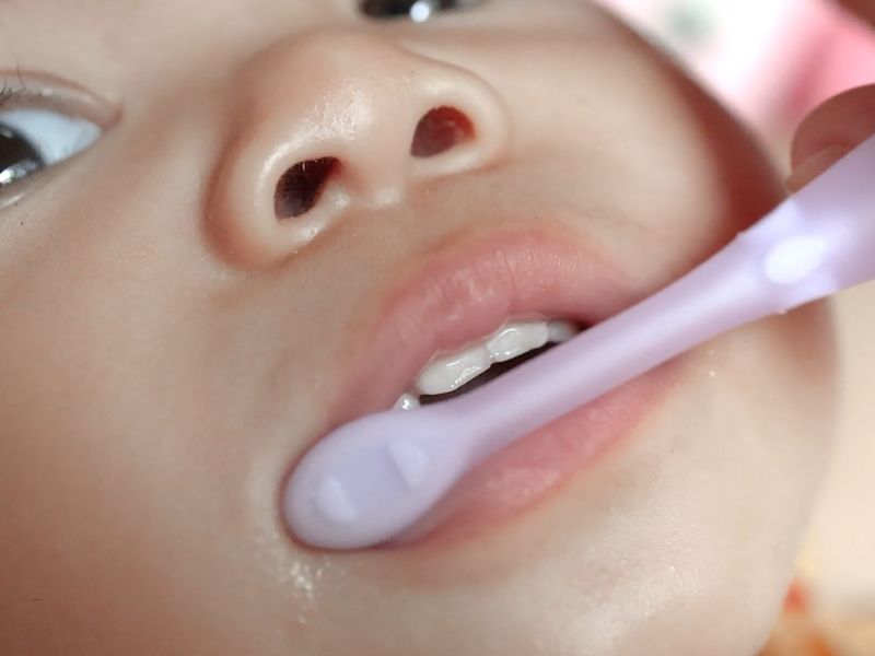 zumiran prikaz bebe kojoj osoba pere zube sa četkicom