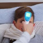 osoba meri temperaturu detetu