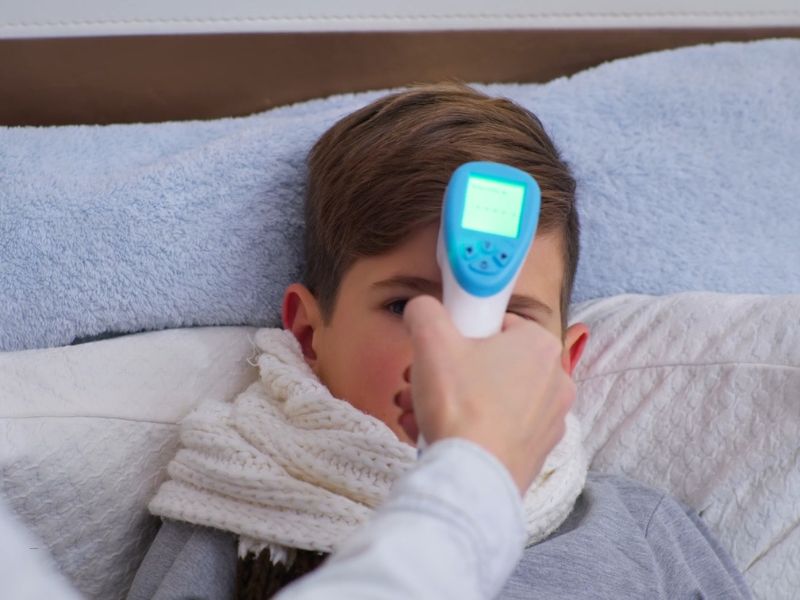 osoba meri temperaturu detetu