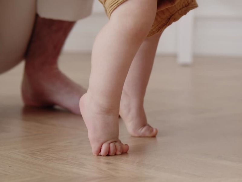 osoba uči bebu da hoda