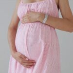 prikaz mame u roze haljini koja grli svoj trudnički stomak