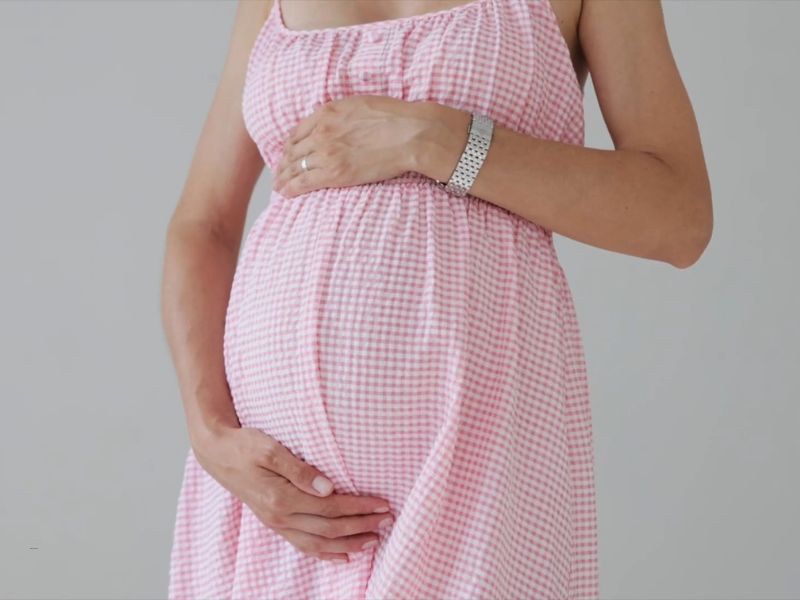 prikaz mame u roze haljini koja grli svoj trudnički stomak