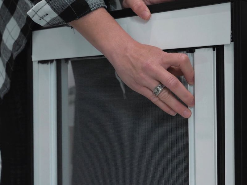 osoba postavlja mrežicu na prozor